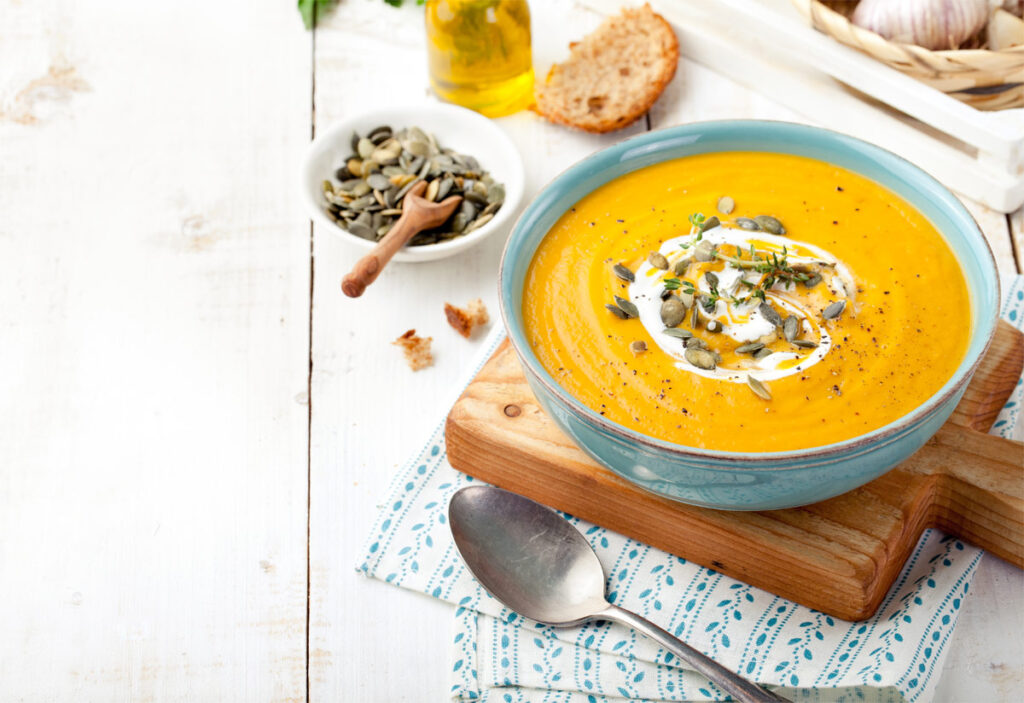 Kürbissuppe auf einem tiefen Teller mit Kürbiskernen und Sahne.