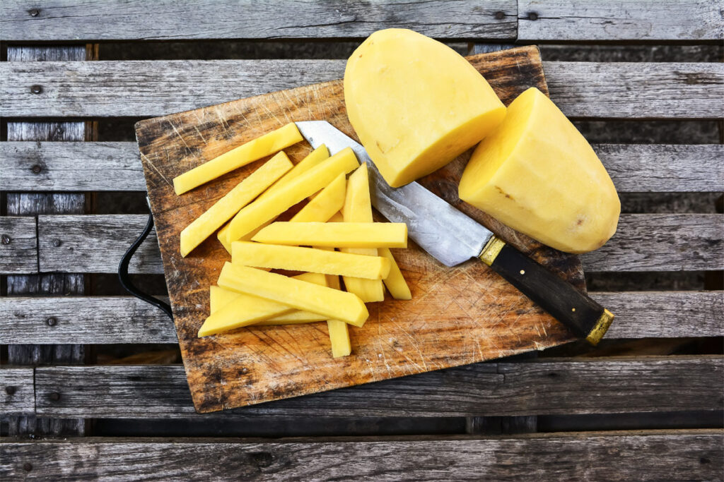 Hausgemachte Pommes auf einem Holzbrett mit Messer