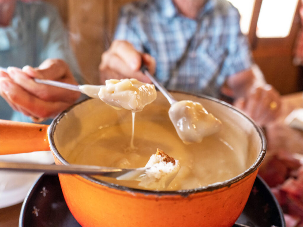 Käsefondue stehend auf dem Tisch mit zwei Gästen.