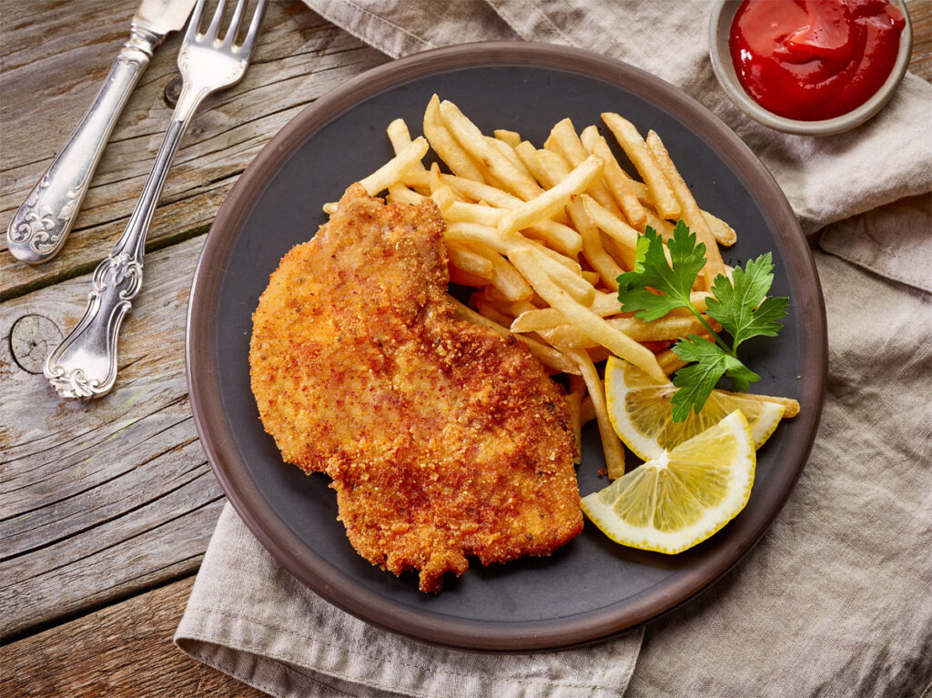 Kalbsschnitzel mit Pommes Frites auf einem Teller.