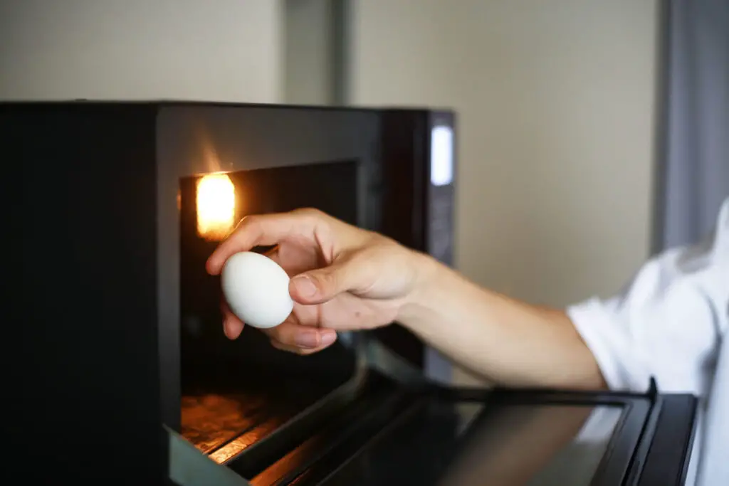 Mann möchte Ei in der Mikrowelle kochen