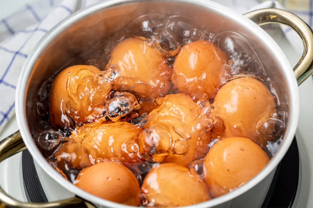 Meherere Eier kochen in einem Topf mit Wasser.