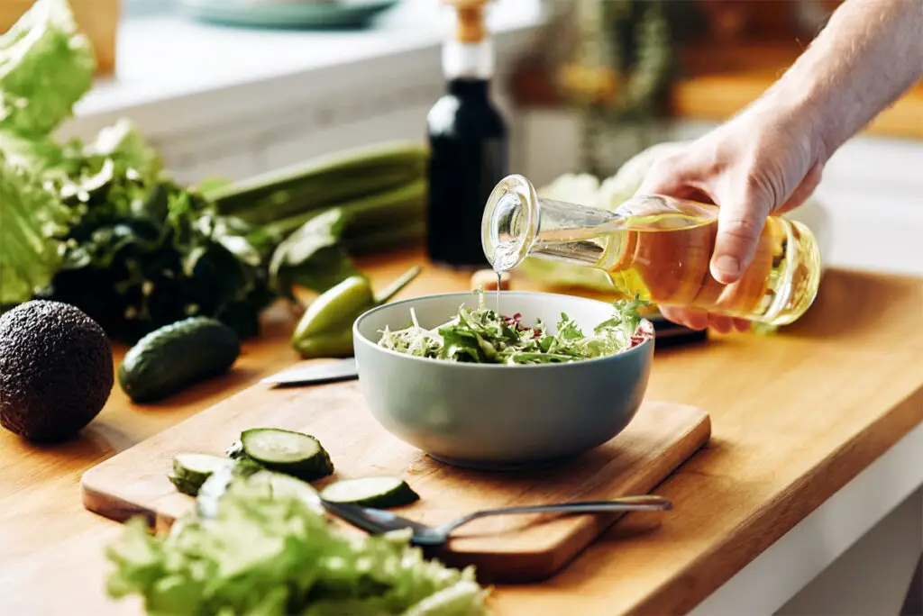 Olivenöl auf Salat in einer blau-grauen Schüssel