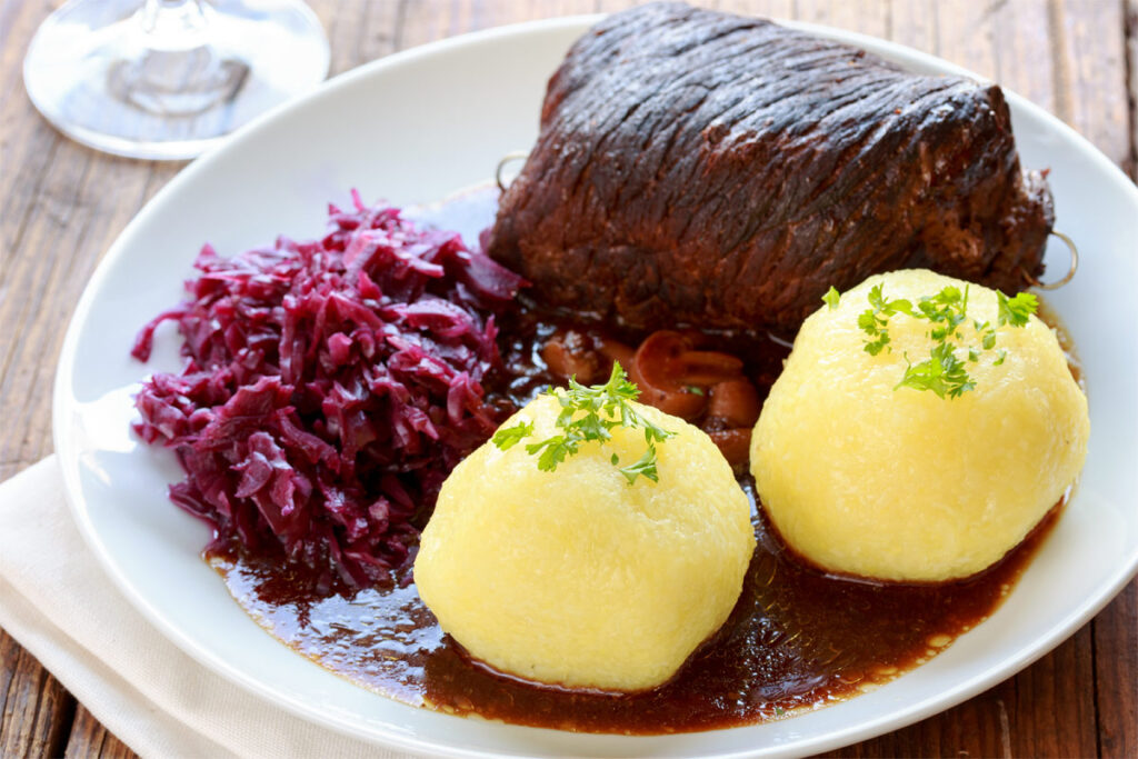 Teller mit Rindsroulade, Rotkohl und Kartoffelklößen.