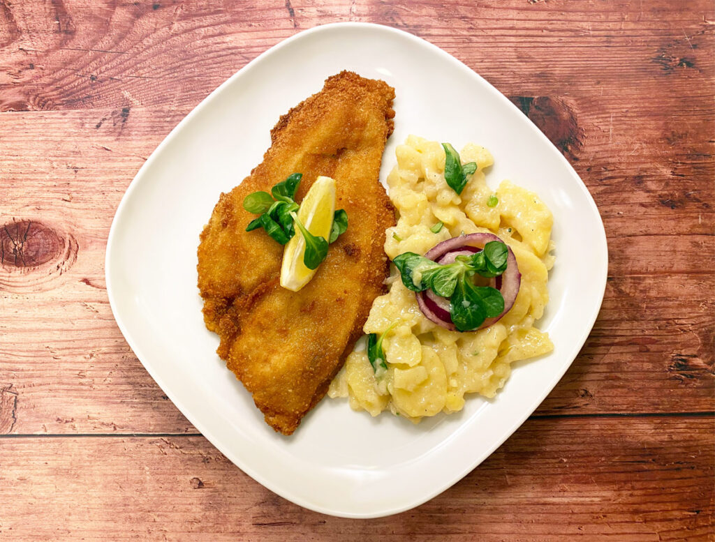 Schollen-Backfisch mit Kartoffelsalat auf einem weißen Teller