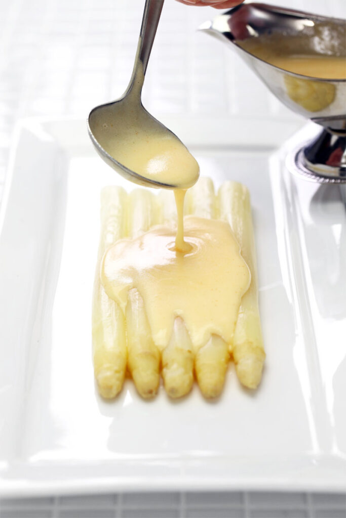 Spargel wird mit Hollandaise übergossen