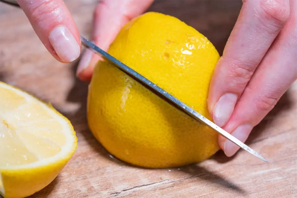 Frau schneidet eine Zitrone in Viertel