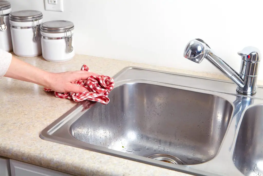 Frau reinigt den Küchen Abfluss
