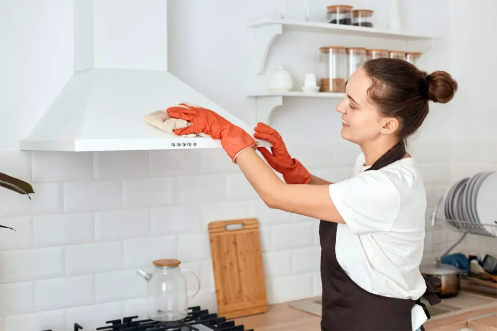 Frau reinigt die Abzugshaube in der Küche