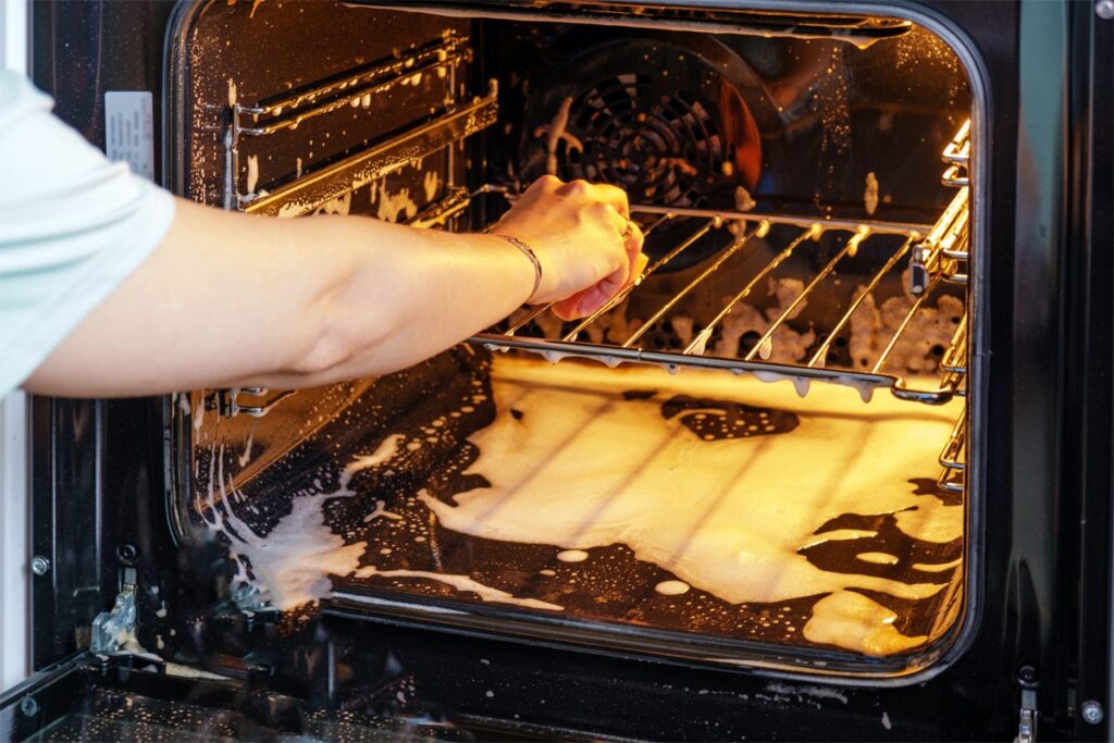 Backofenrost reinigen im Backofen druch eine Frau