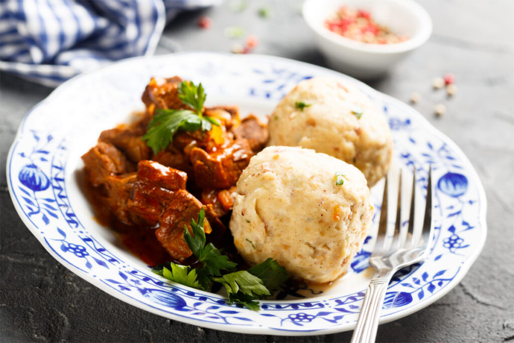 Teller mit Gulasch und zwei Knödeln