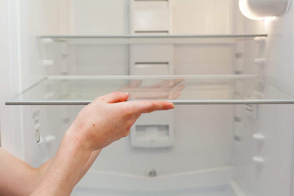 Frau reinigt die Glasscheiben im Kühlschrank