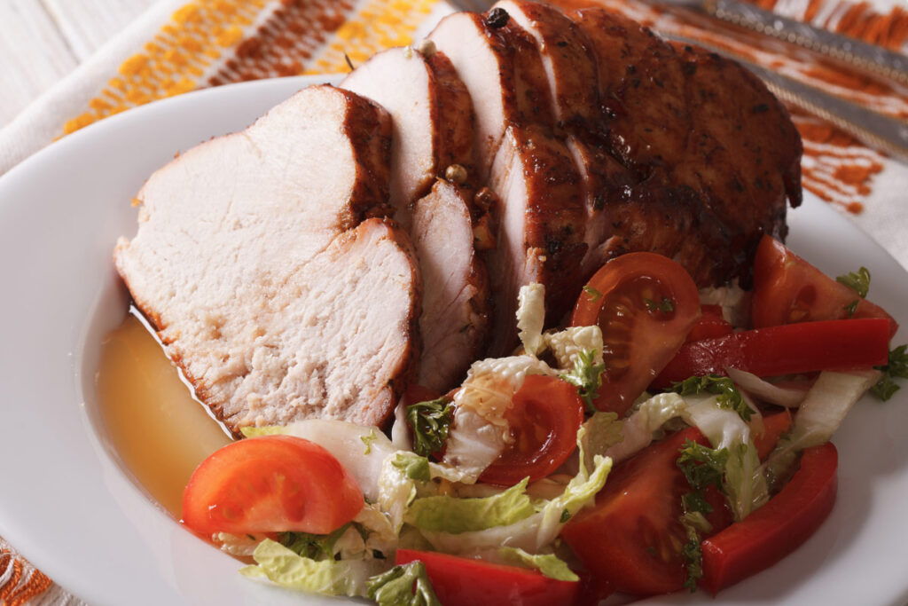 Gebackene Putenbrust mit Salat auf einem weißen Teller