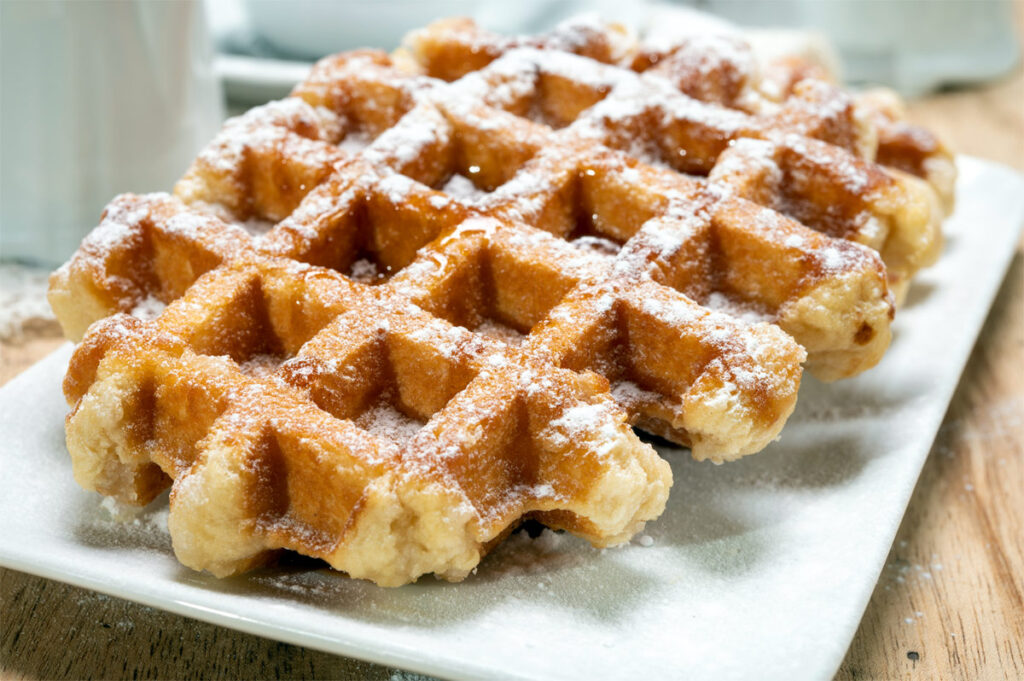 Eine Waffel ohne Mehl mit Puderzucker auf einem weißen Teller