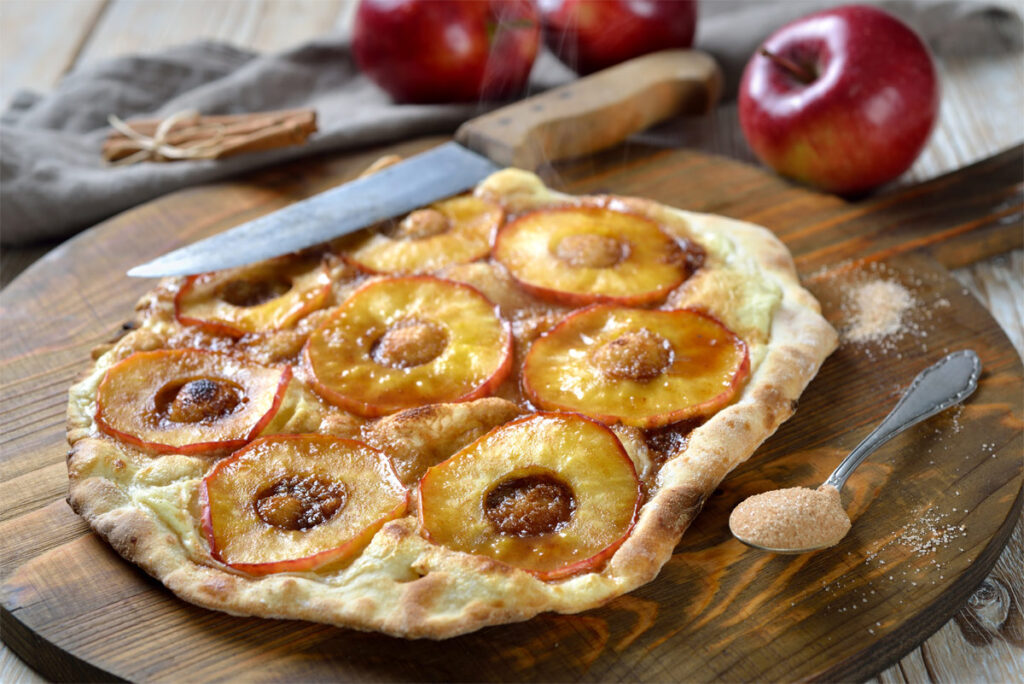 Flammkuchen mit Apfel und Zimt auf einem Holzbrett