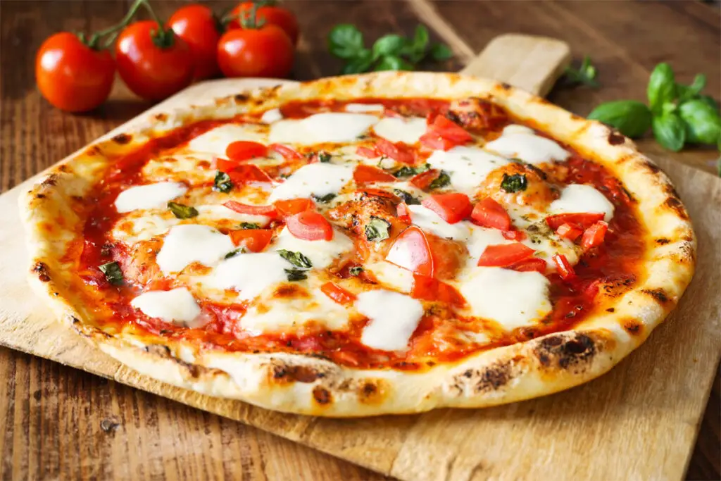 Pizza mit Tomaten und Mozzarella auf einem Holzbrett