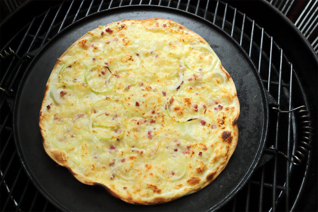 Tarte Flambée. Fertig gebackener Flammkuchenteig mit Belag.