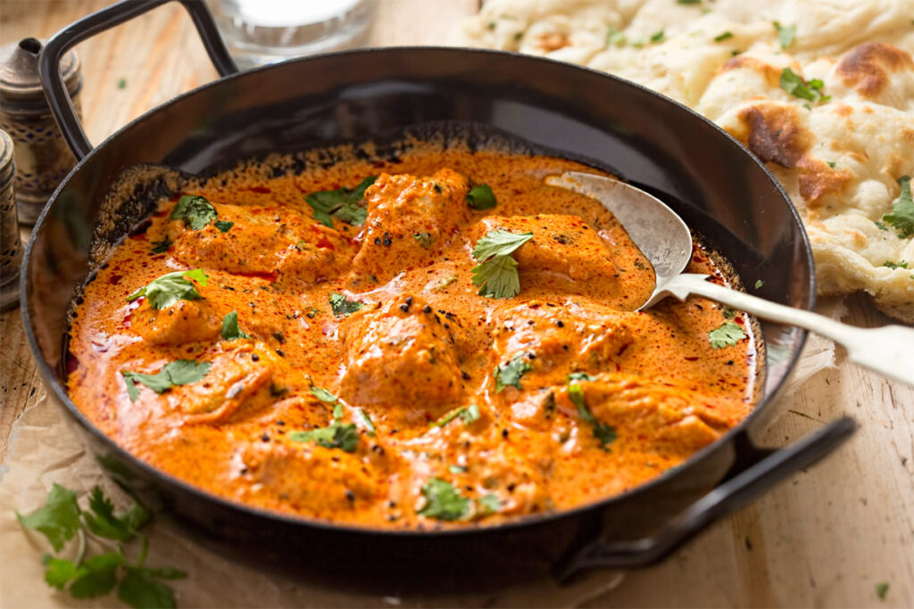 Schwarze Pfanne mit Hähnchen Curry und Naan-Brot