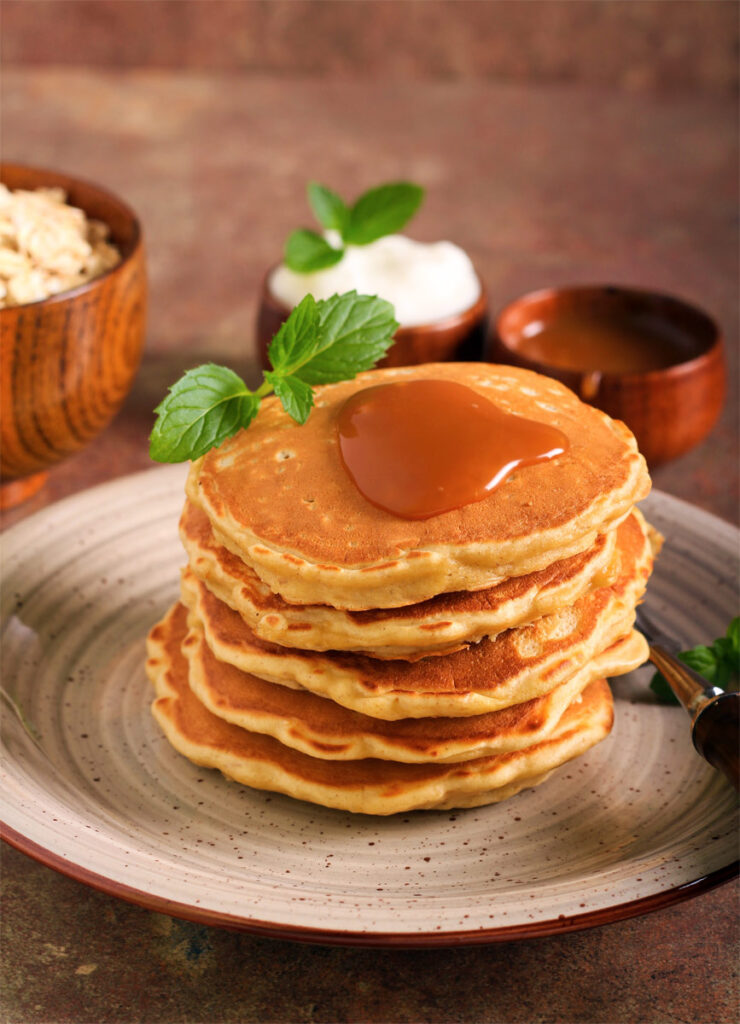 Teller mit mehreren Bananen Haferflocken Pancakes übereinander gestapelt