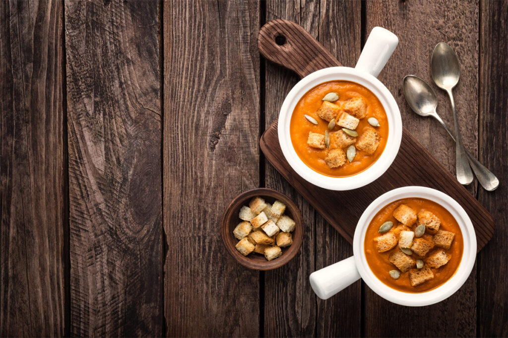 Schüsseln mit Kürbissuppe und Croutons