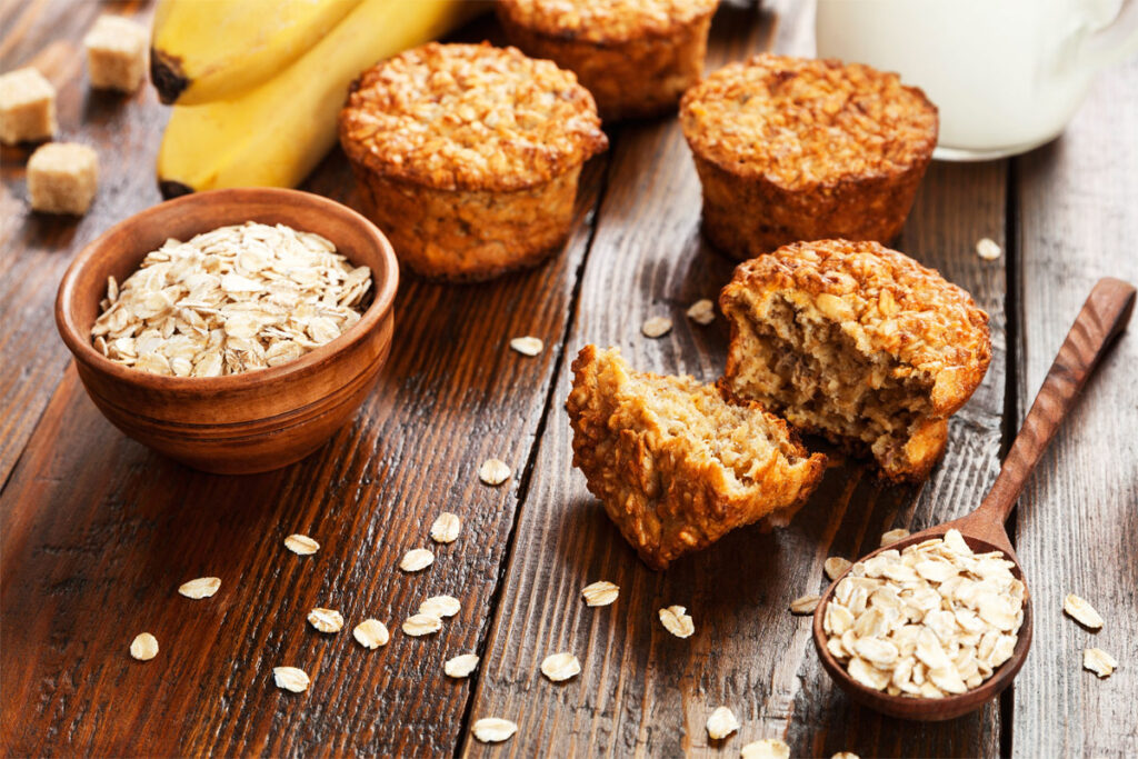 Haferflocken Muffins liegen auf dem Tisch mit einer Schüssel Haferflocken.