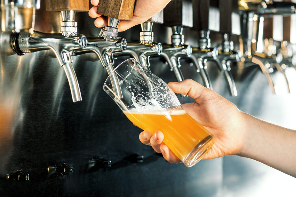 Ein Mann zapft ein Glas Bier aus einer Zapfanlage.