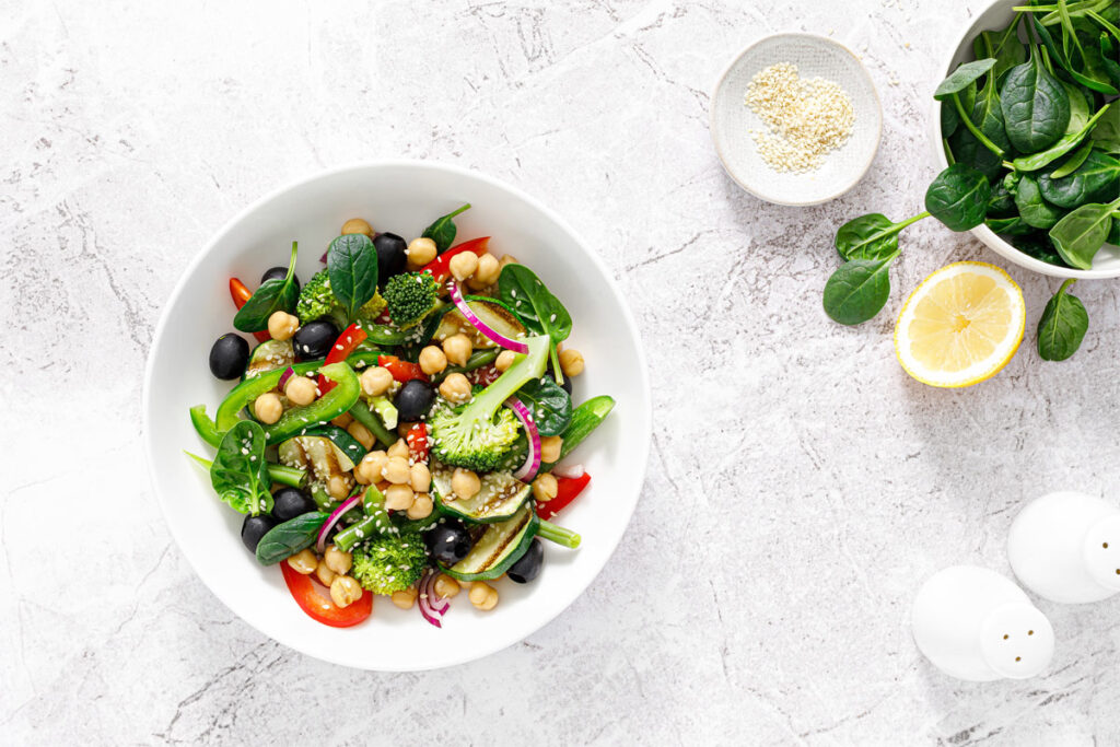 Ein veganer Gemüsesalat mit Kichererbsen und Spinat. Und mit Brokkoli, Paprika, Oliven und gegrillten Zucchini.