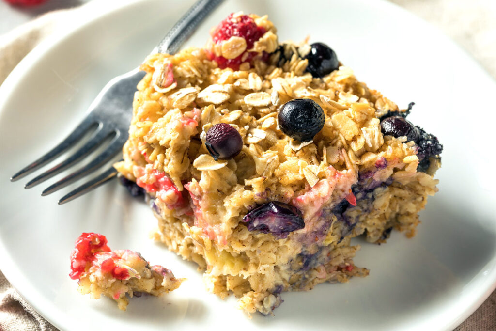 Ein Stück Haferflockenauflauf Baked Oats auf einem weißen Teller mit Gabel.