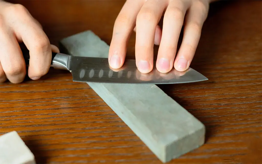 Küchenmesser schärfen mit einem Wetzstahl auf dem Tisch.